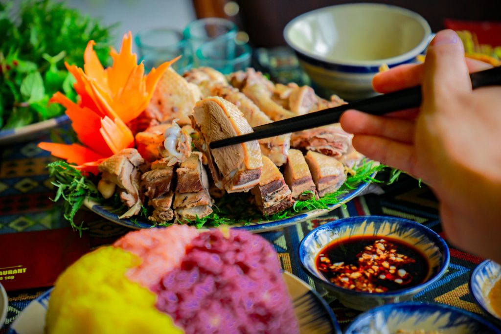 Close-up of a colorful Vietnamese meal with chopsticks and dipping sauce.