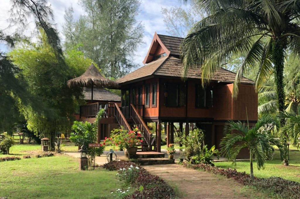 Charming traditional Thai wooden house surrounded by tropical garden landscape.